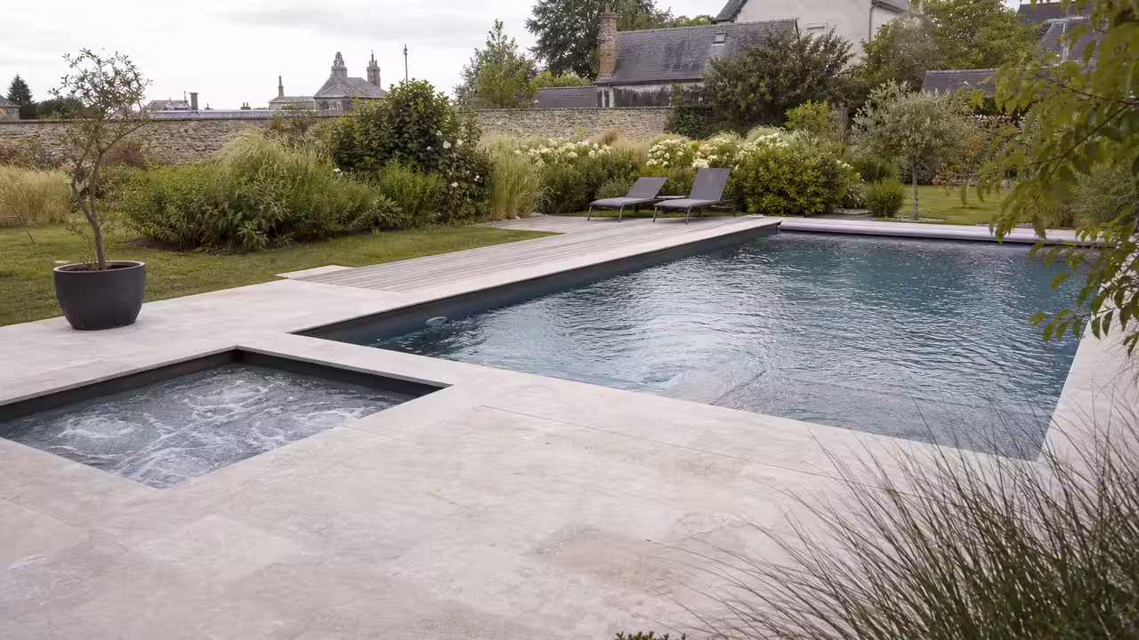 Piscine rectangulaire contemporaine avec terrasse minérale et spa encastré dans un jardin paysager d’Angers