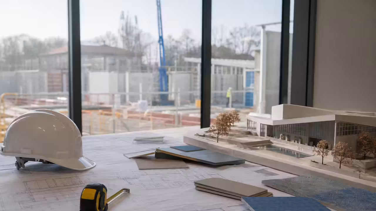 Plans architecturaux et casque de chantier préparant la construction d’une piscine municipale