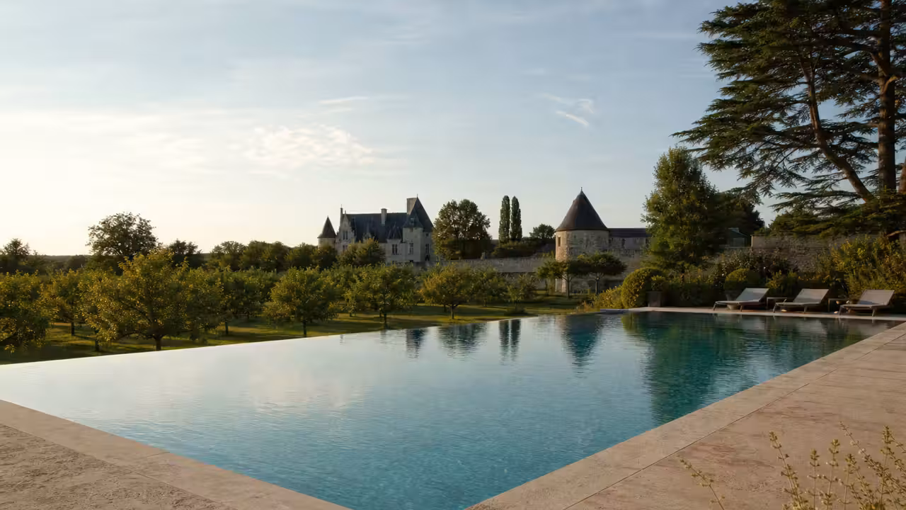 Piscine à débordement bordée de pierre et de végétation dans le parc d’un château de la Loire