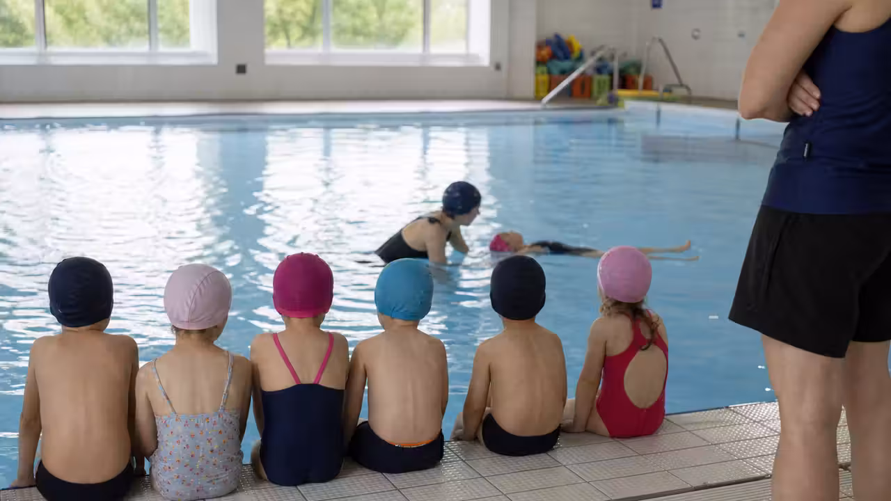 Groupe d’enfants de maternelle encadré au bord d’un petit bassin lors d’une séance de découverte aquatique