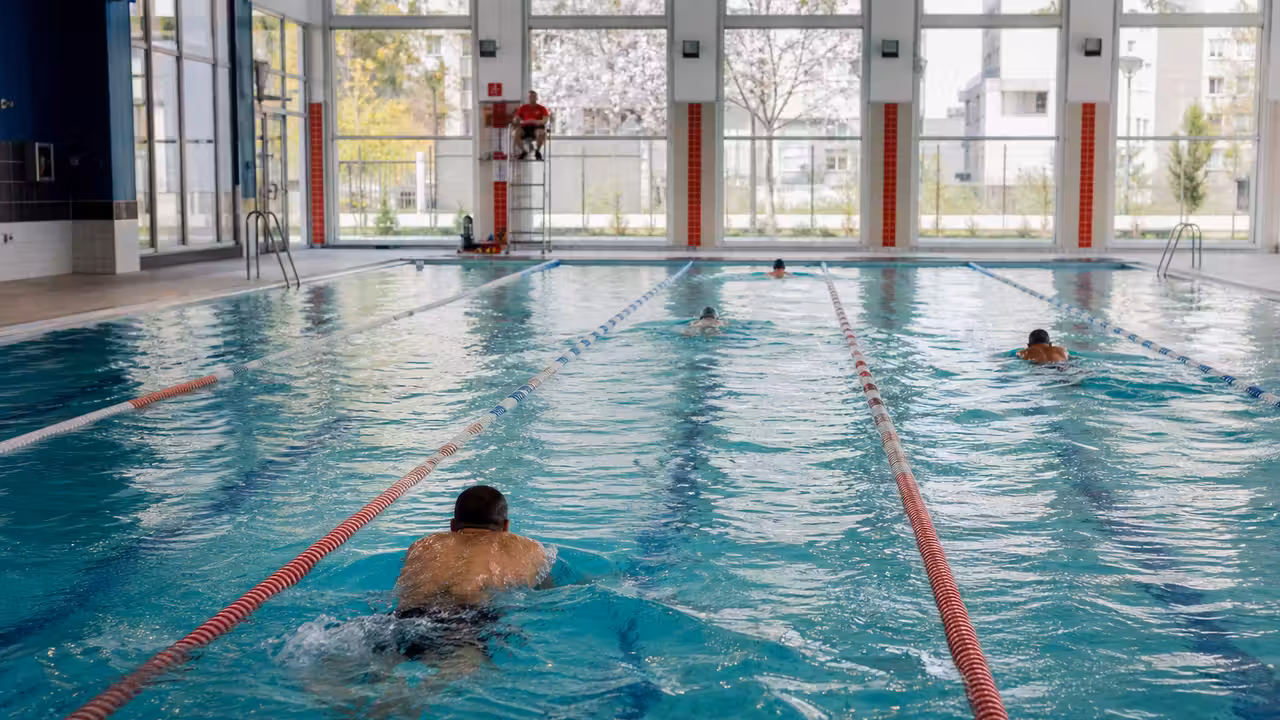 Nageurs dans les lignes d’eau d’une piscine publique lumineuse, avant une séance de nage libre