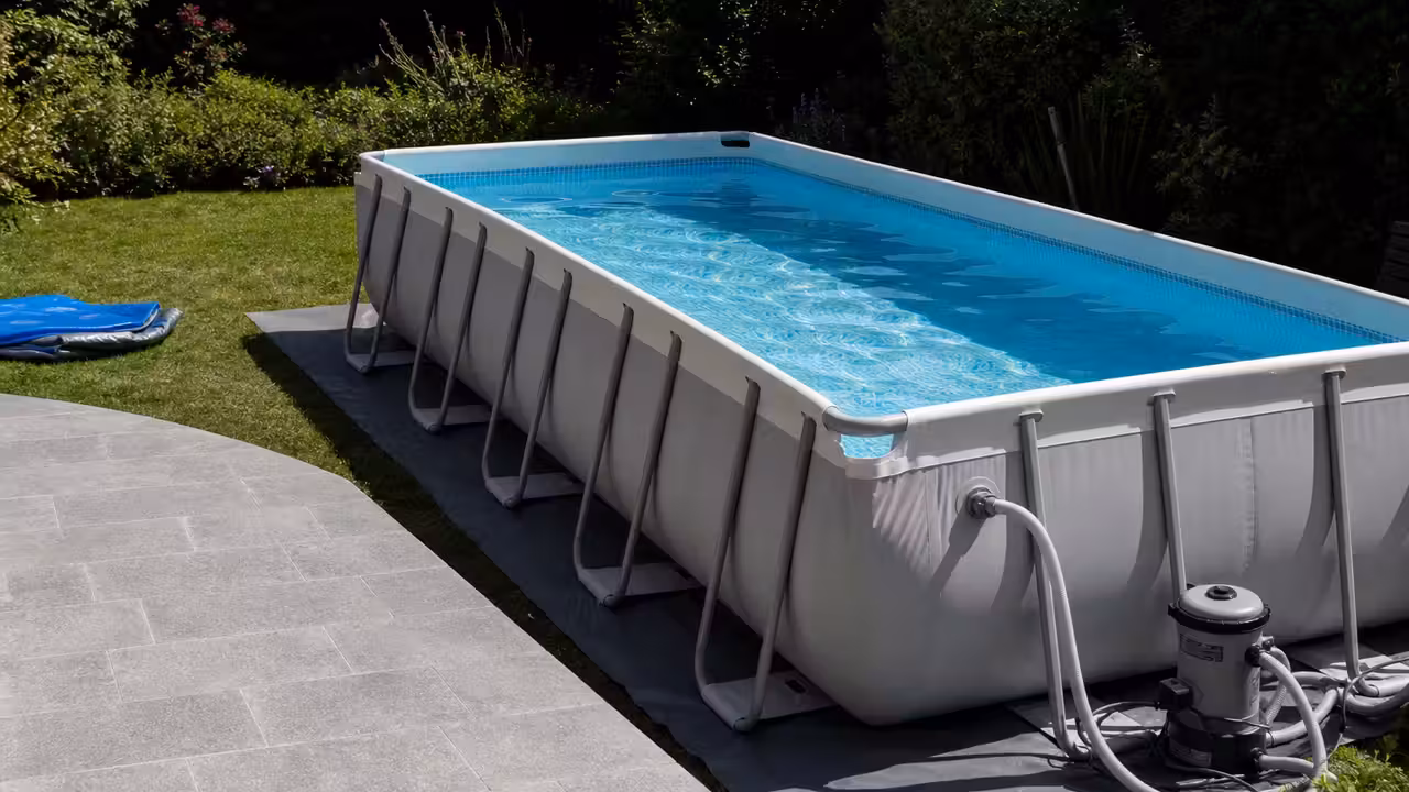 Piscine hors-sol tubulaire installée sur un jardin nivelé, avec bâche et système de filtration visibles