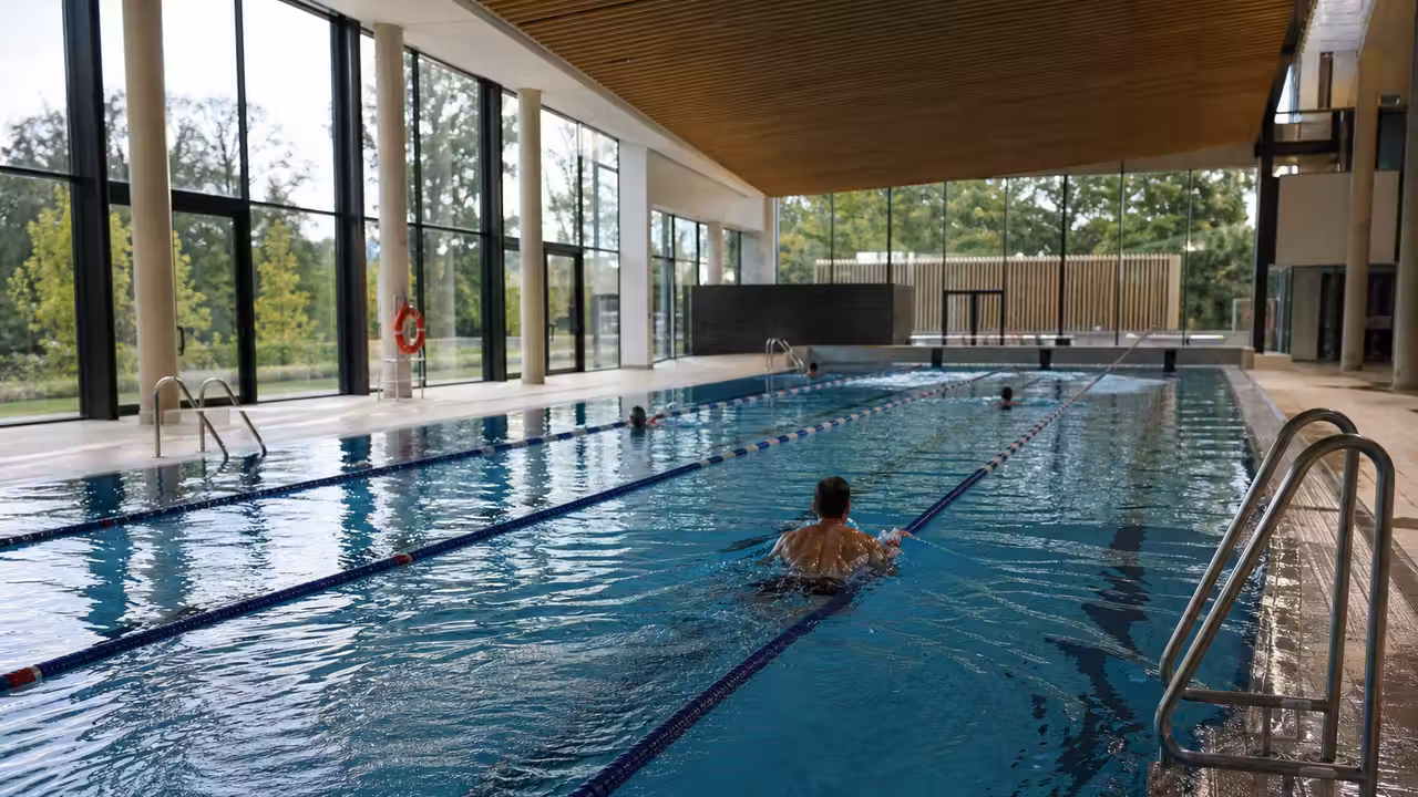 Bassin sportif lumineux de 25 mètres dans un centre aquatique municipal rénové, avec lignes d’eau vides