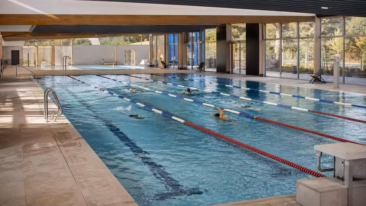 Bassins intérieurs d’une piscine publique moderne avec lignes de nage, espace loisirs et lumière naturelle