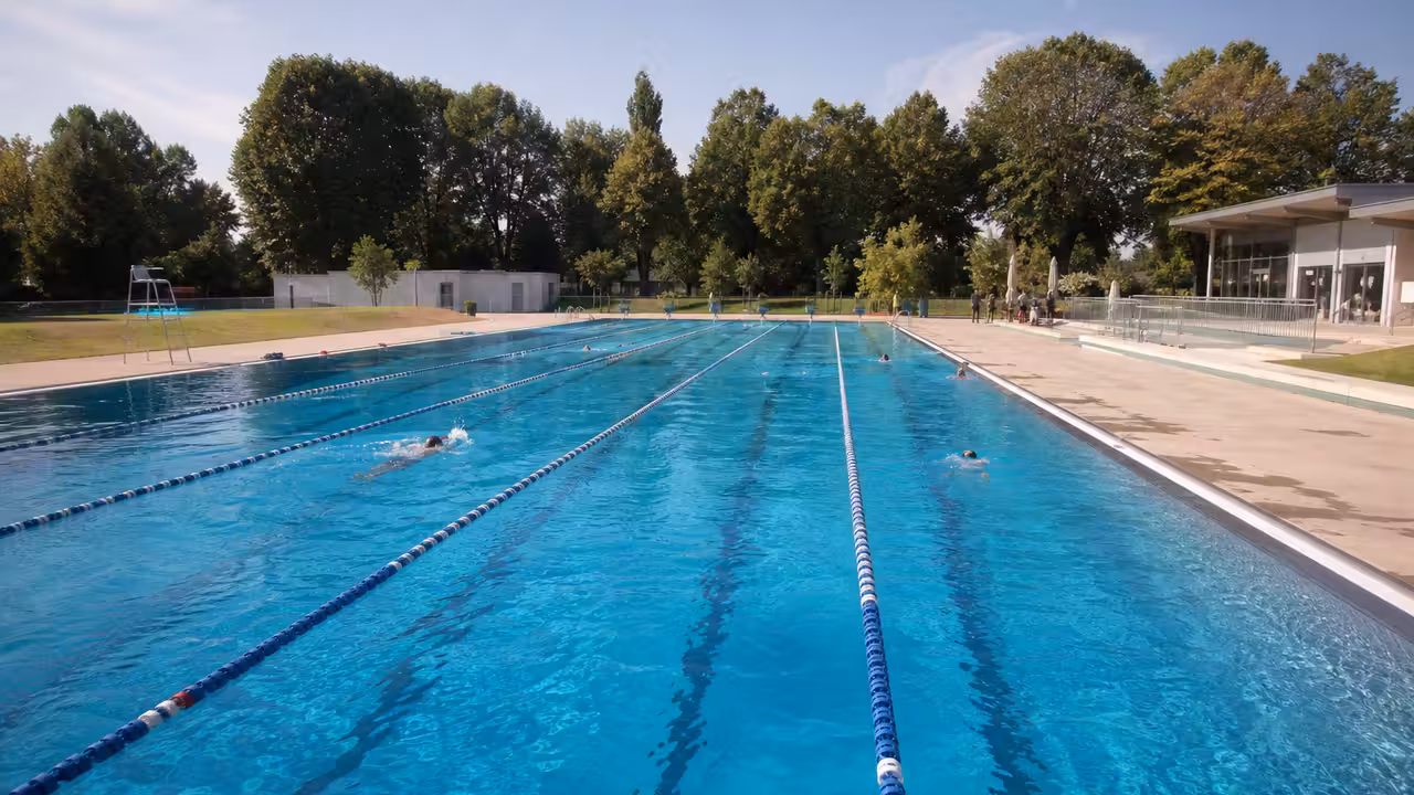 Bassin extérieur de 50 mètres d’un stade nautique avec lignes d’eau, plages minérales et pelouse arborée