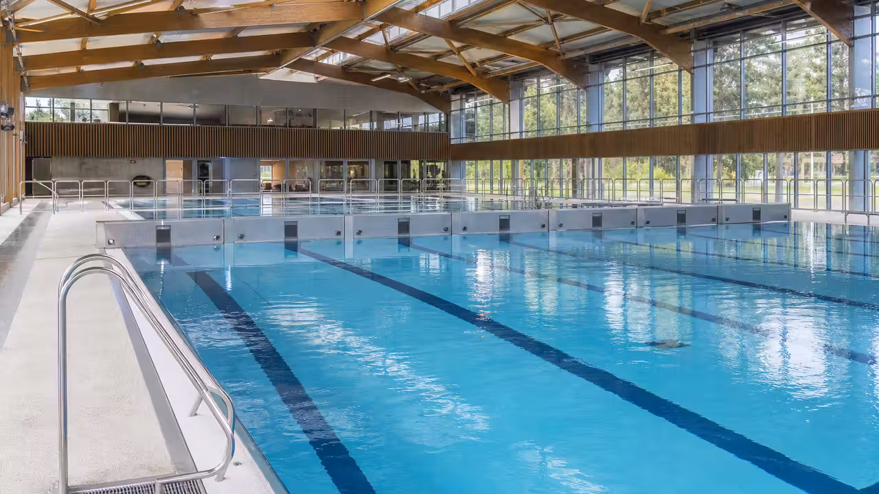 Grand bassin intérieur à couloirs, séparé par un pont mobile dans un centre aquatique contemporain