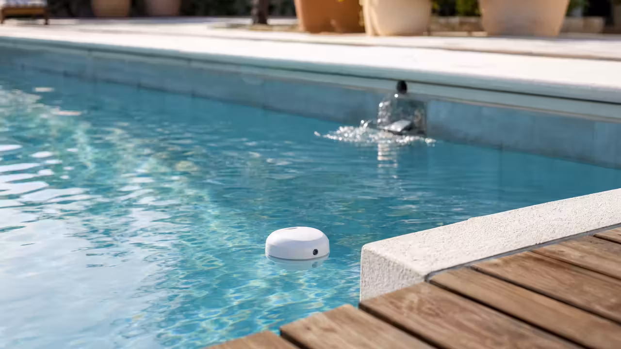 Sonde connectée flottante dans une piscine familiale, près d’une eau claire et d’une terrasse en bois