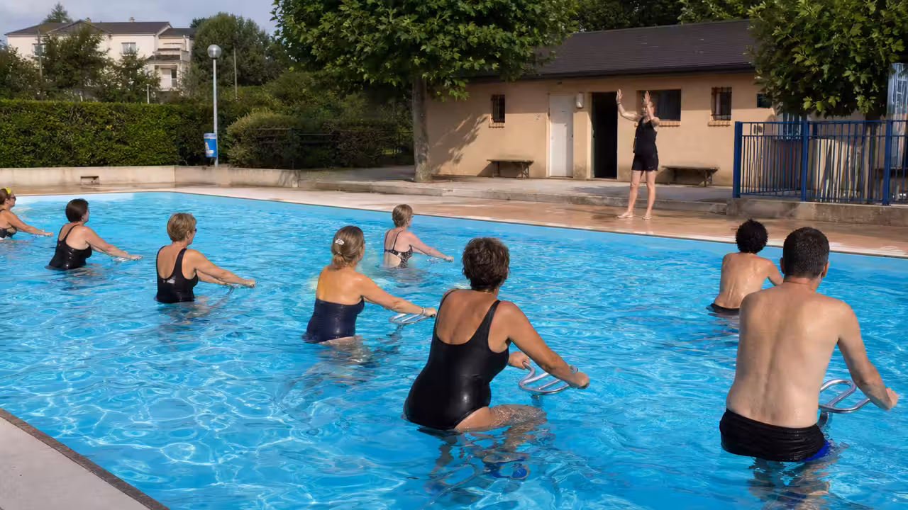 Séance collective d’aquabike dans une piscine extérieure municipale par une lumineuse journée d’été
