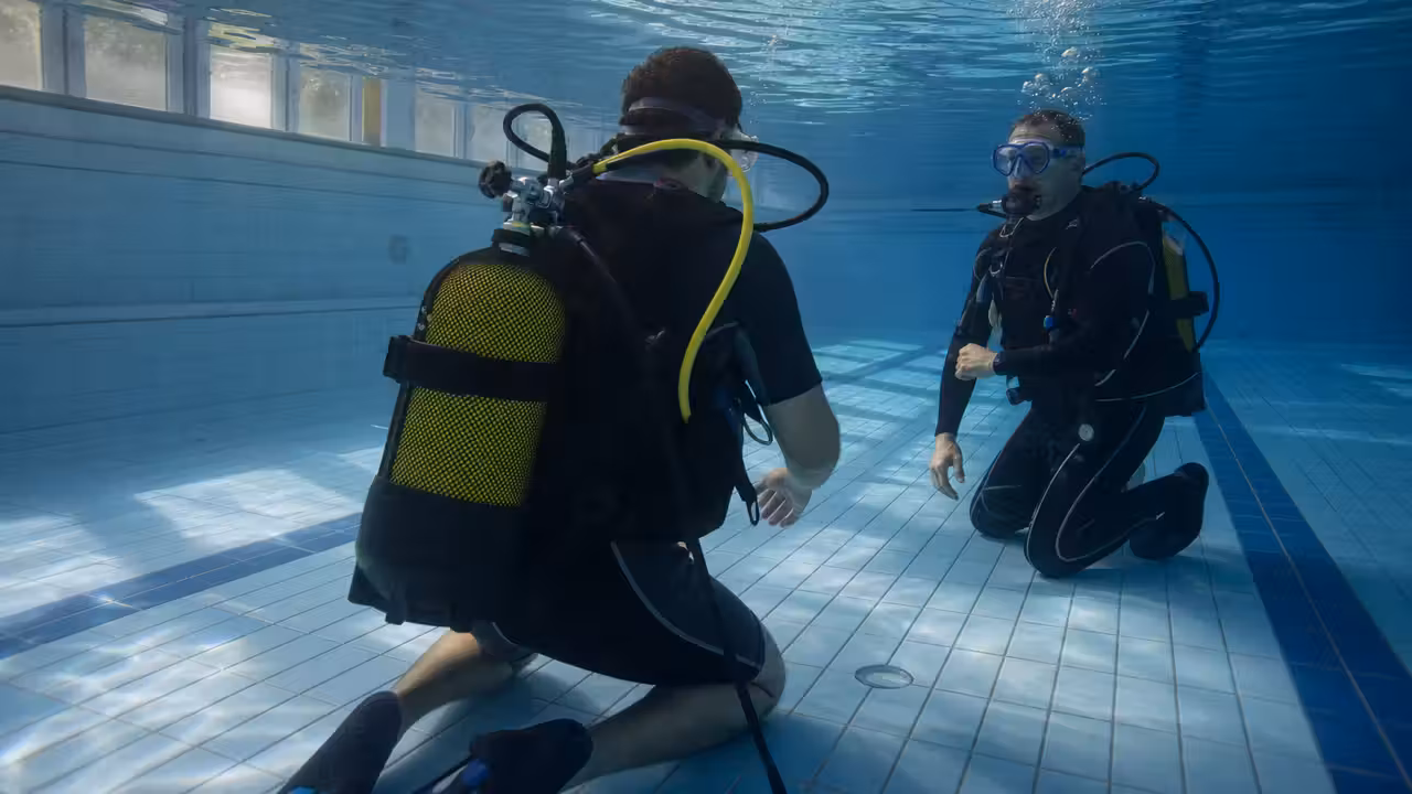 Plongeur débutant accompagné par un moniteur lors d’une initiation à la plongée dans un bassin couvert