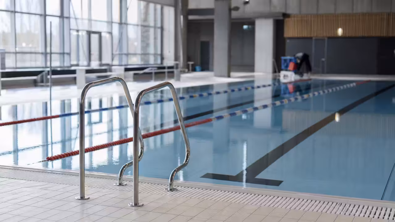Bassin intérieur d’une piscine publique avec lignes d’eau, gradins et lumière naturelle en arrière-plan