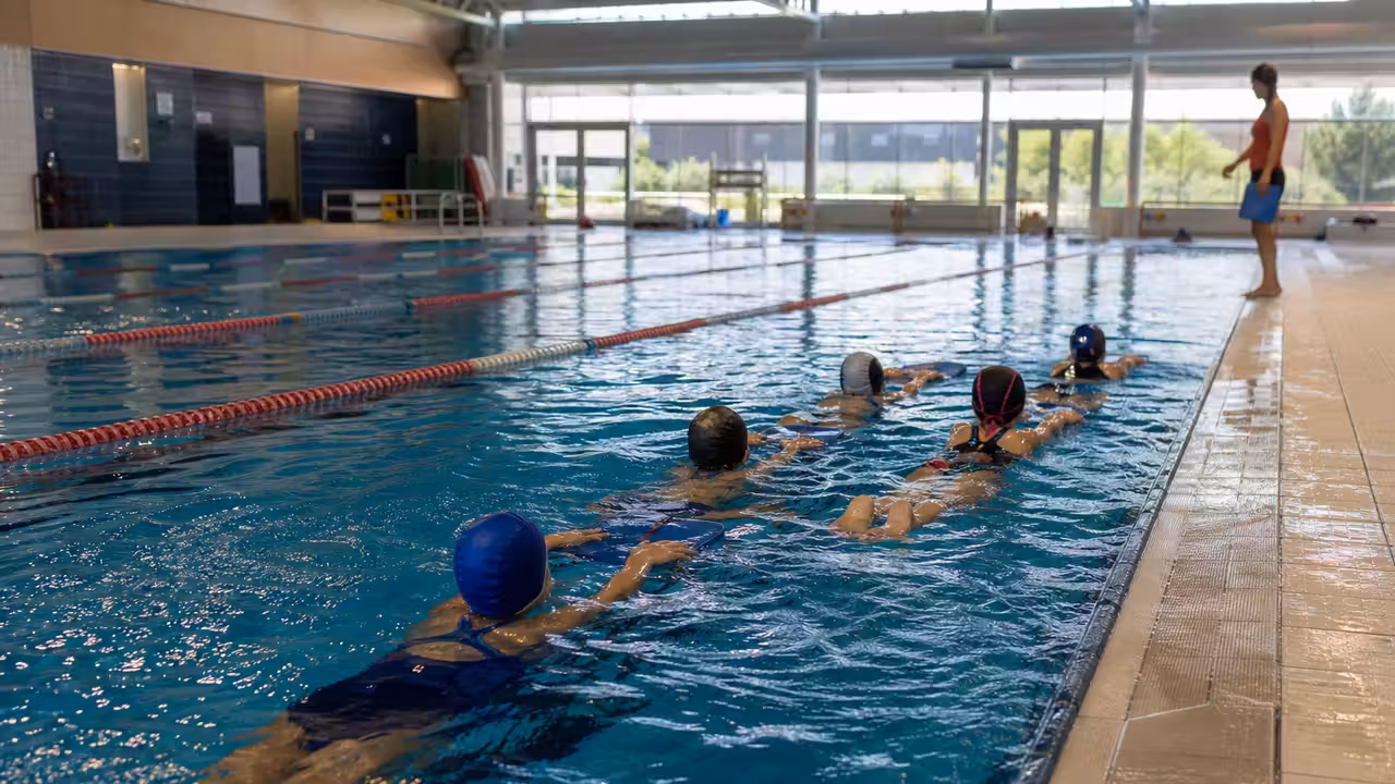 Ligne d’eau d’une piscine municipale avec un groupe en cours de natation encadré depuis le bassin