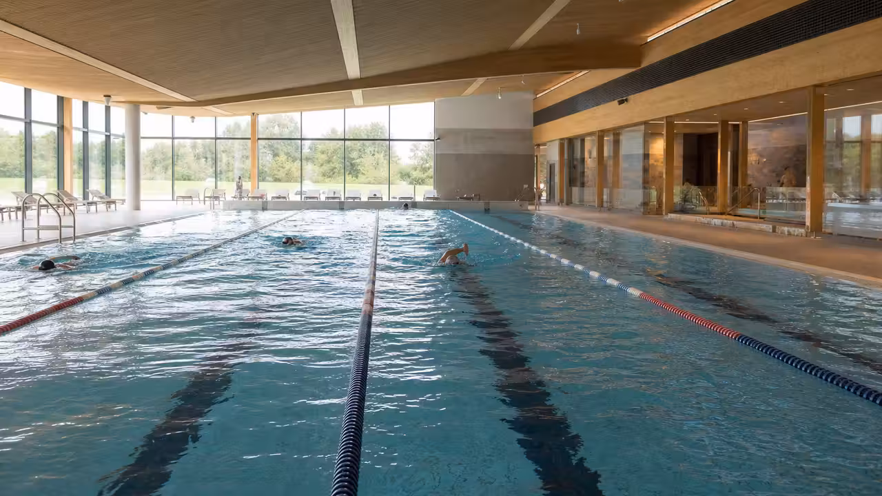 Bassin intérieur lumineux d’un centre aquatique avec lignes d’eau et espace de détente en arrière-plan