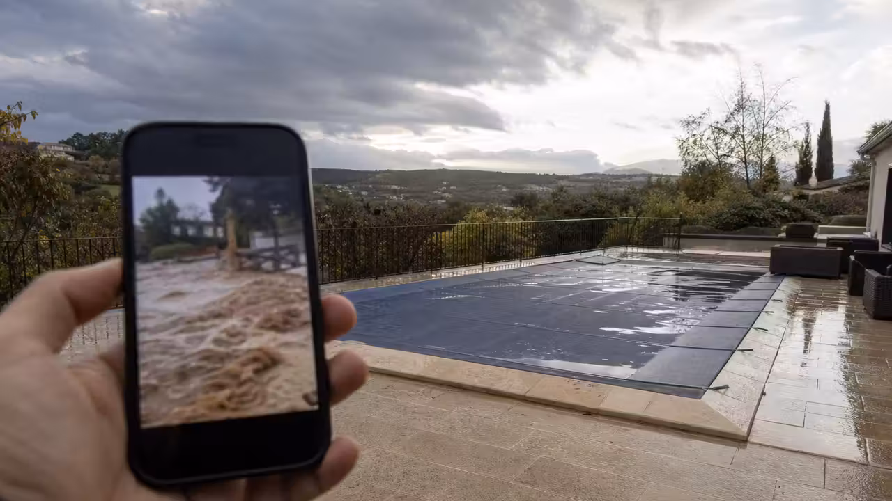 Un smartphone affichant une vidéo d’inondation non vérifiée près d’une piscine extérieure fermée
