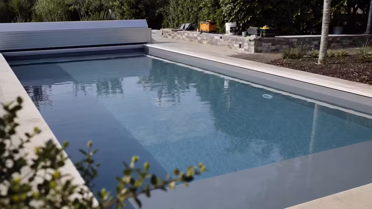 Piscine rectangulaire en rénovation avec liner gris, margelles claires et volet roulant fermé