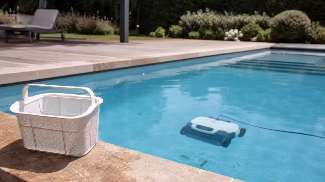 Robot électrique nettoyant le fond d’une piscine familiale, avec son panier filtrant au premier plan