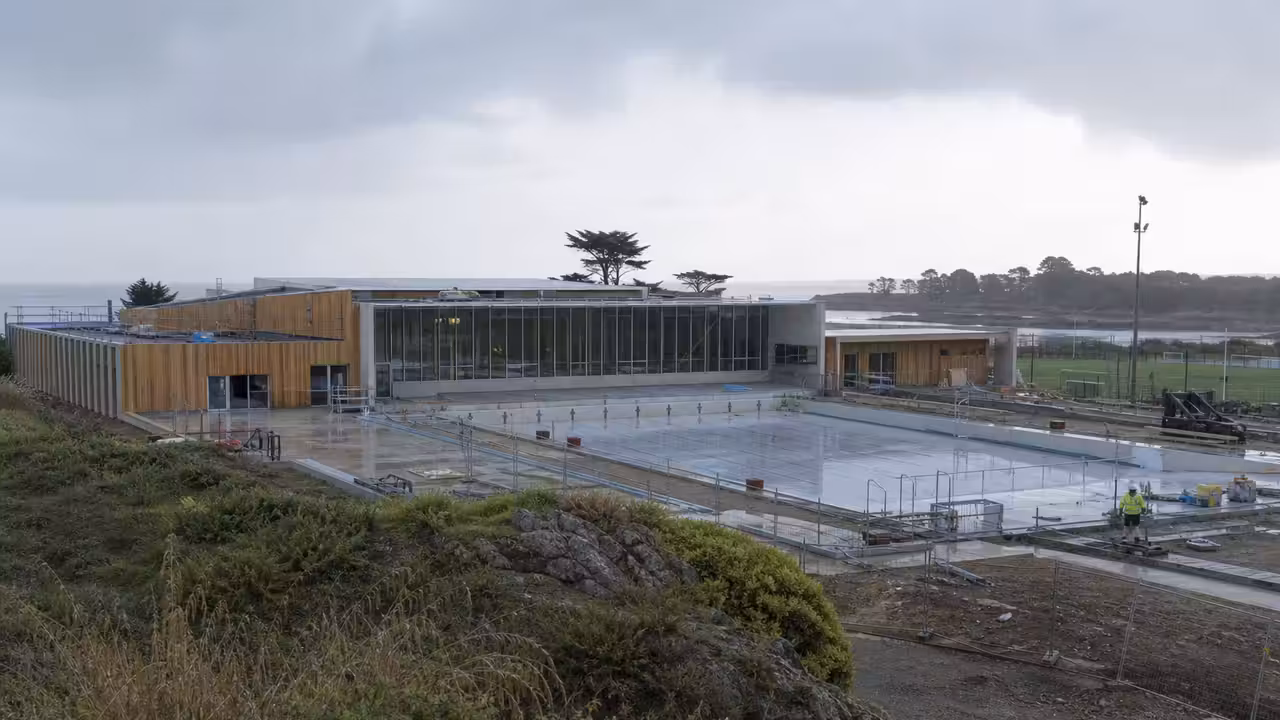 Projet de centre aquatique public contemporain près d’un complexe sportif, avec bassin extérieur et végétation côtière