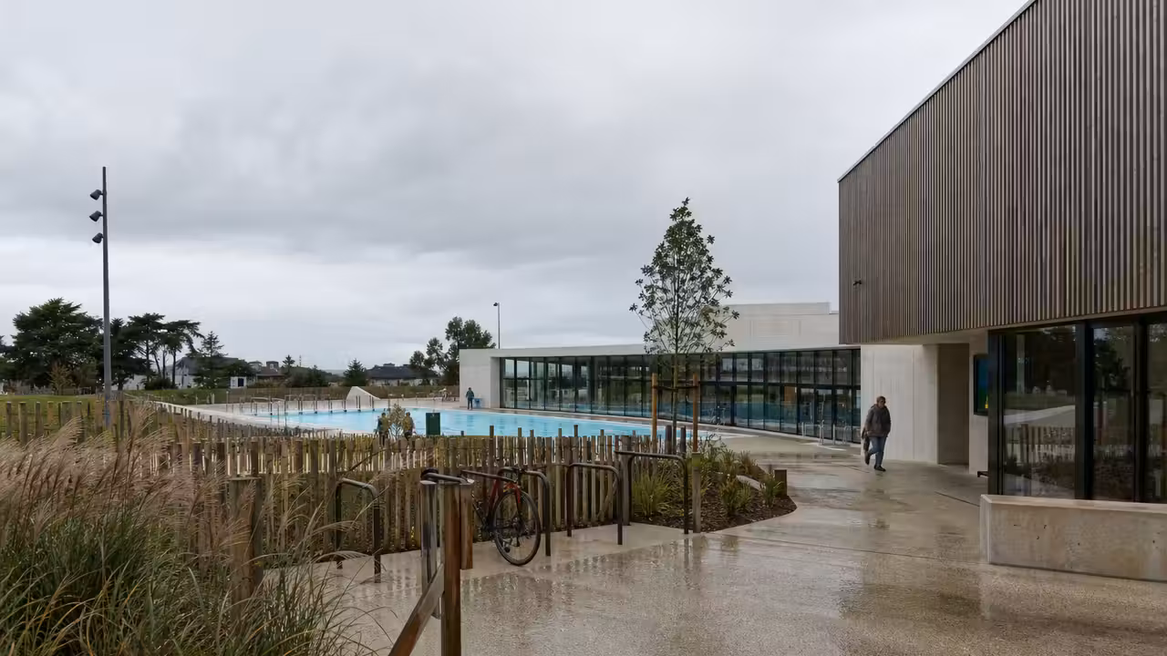 Perspective réaliste d’une piscine publique moderne avec bassin extérieur, bâtiment vitré et espaces paysagers