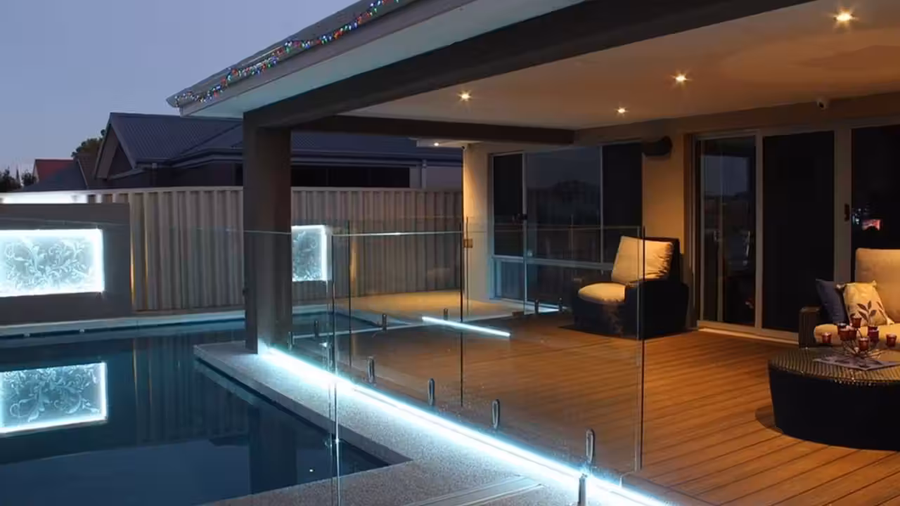 Piscine contemporaine éclairée par des projecteurs LED blancs, avec terrasse minérale au crépuscule