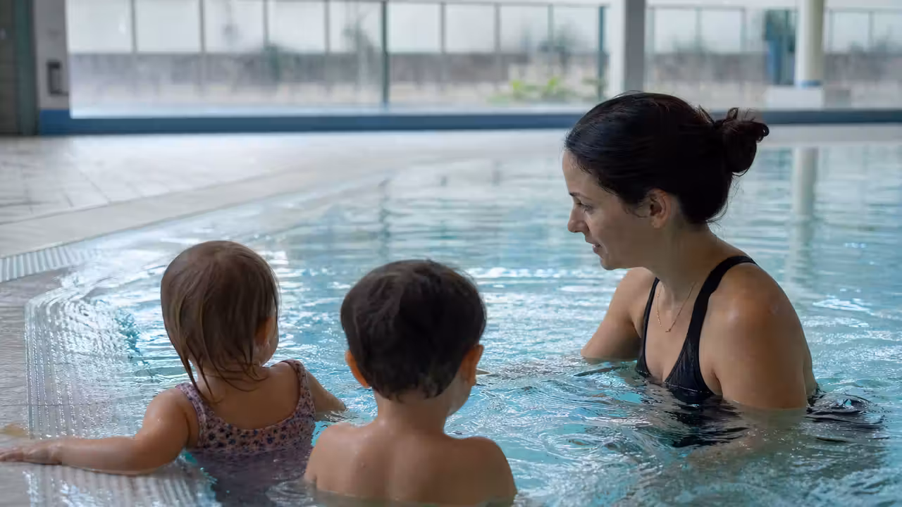 Encadrante accompagnant de jeunes enfants dans un bassin peu profond lors d’un atelier d’aisance aquatique