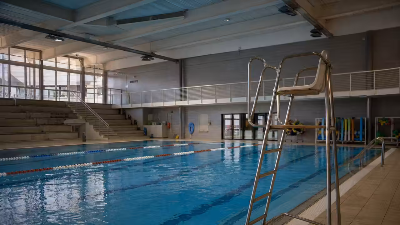 Bassin municipal couvert avec lignes de nage et poste de surveillance vide lors d’une fermeture au public
