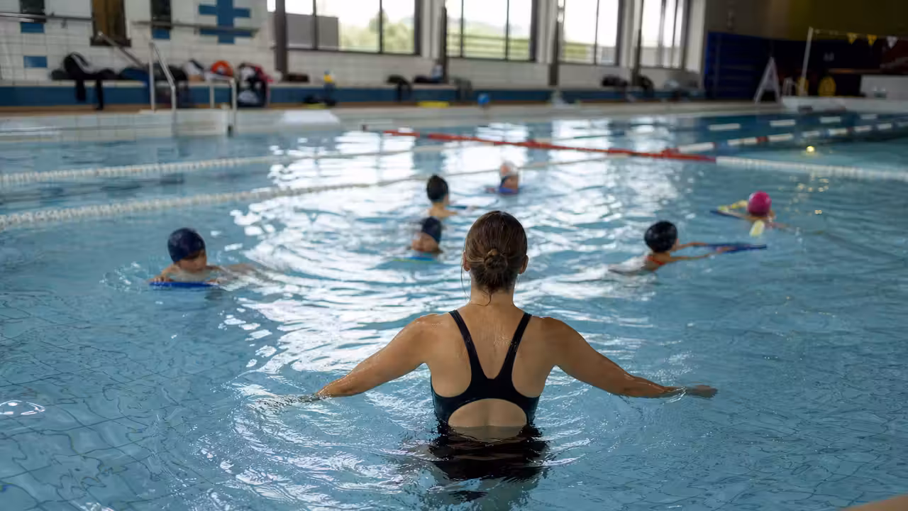 Jeune groupe d’enfants encadré par un maître-nageur lors d’un cours en piscine intérieure
