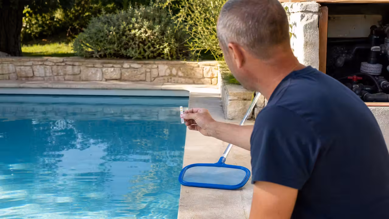 Propriétaire contrôlant l’eau d’une piscine avec une bandelette de test près du local technique