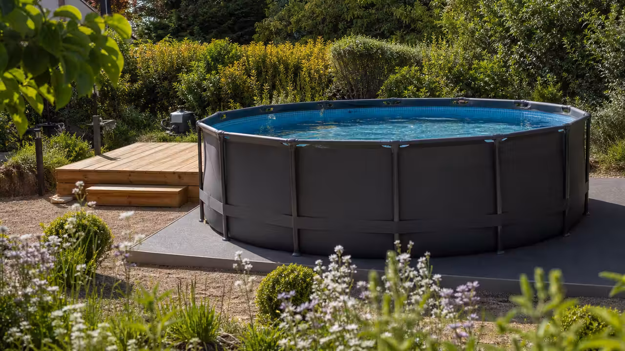 Piscine hors sol tubulaire installée sur un jardin nivelé, avec terrasse en bois et filtration discrète