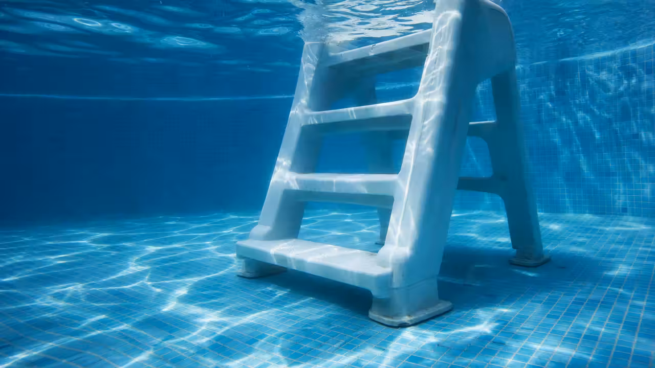 Escalier amovible en plastique blanc immergé dans une piscine, légèrement incliné sur le fond du bassin