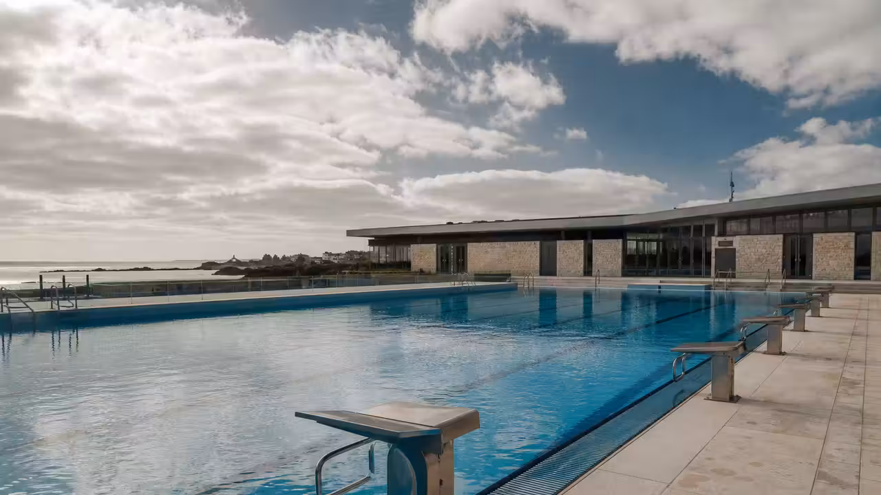 Couloirs d’un bassin extérieur chauffé de 50 mètres dans un centre aquatique sous un ciel breton clair