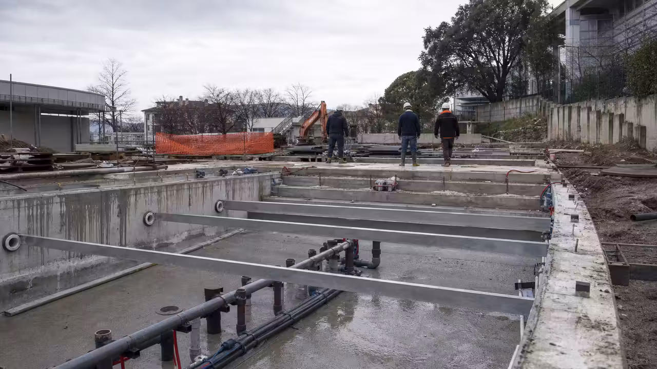 Bassin public vide en cours de rénovation, avec réseaux techniques et lumière naturelle sur les carrelages