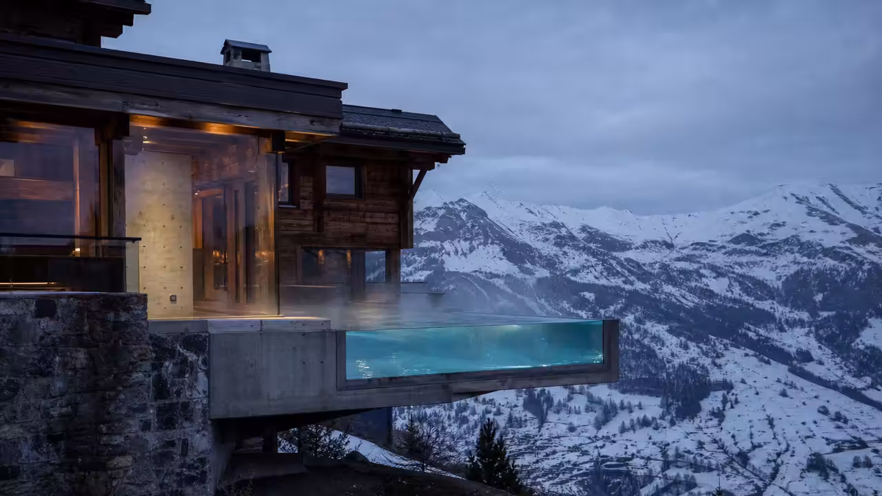 Piscine suspendue aux parois transparentes intégrée à un chalet contemporain face aux sommets alpins