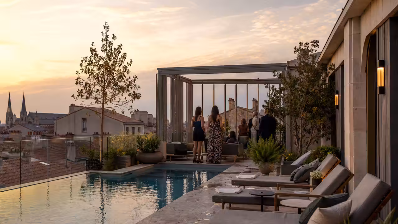Piscine sur un rooftop urbain au coucher du soleil, avec transats et terrasse dégagée