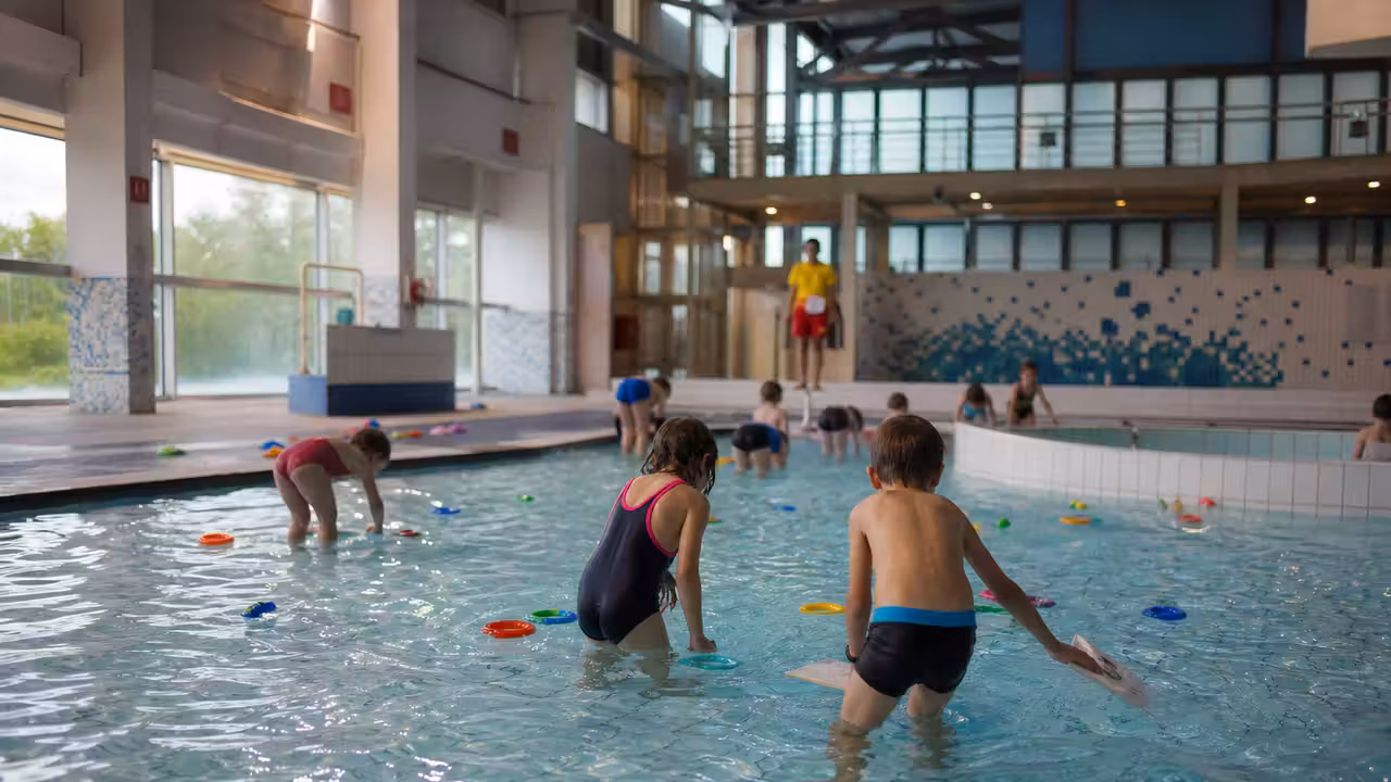 Enfants en équipes cherchent des indices flottants dans un bassin surveillé lors d’une animation ludique