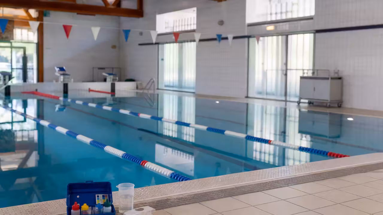 Bassin intérieur de piscine publique vide, lignes d’eau calmes et matériel de contrôle posé au bord
