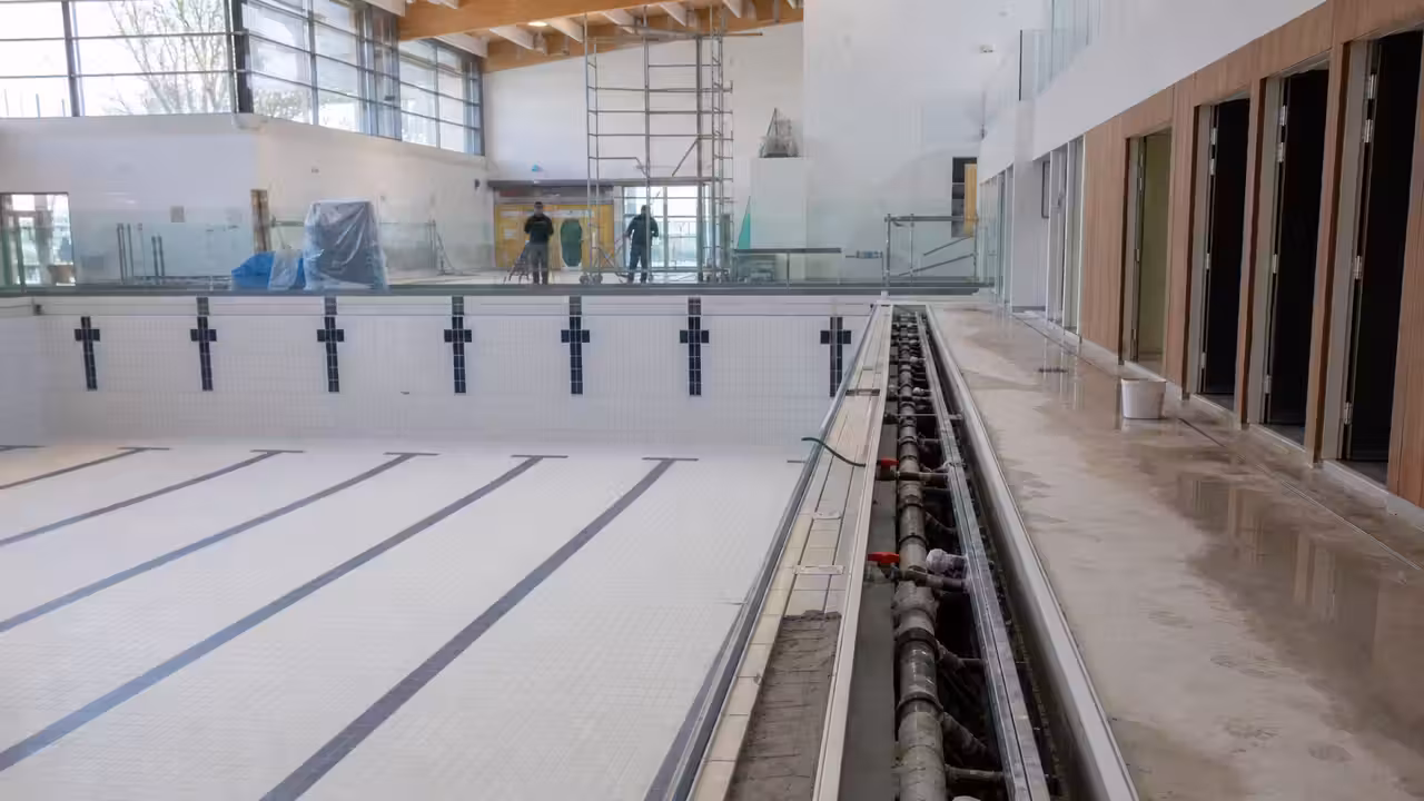 Bassin municipal vide en cours de rénovation, avec vestiaires et installations techniques temporairement fermés