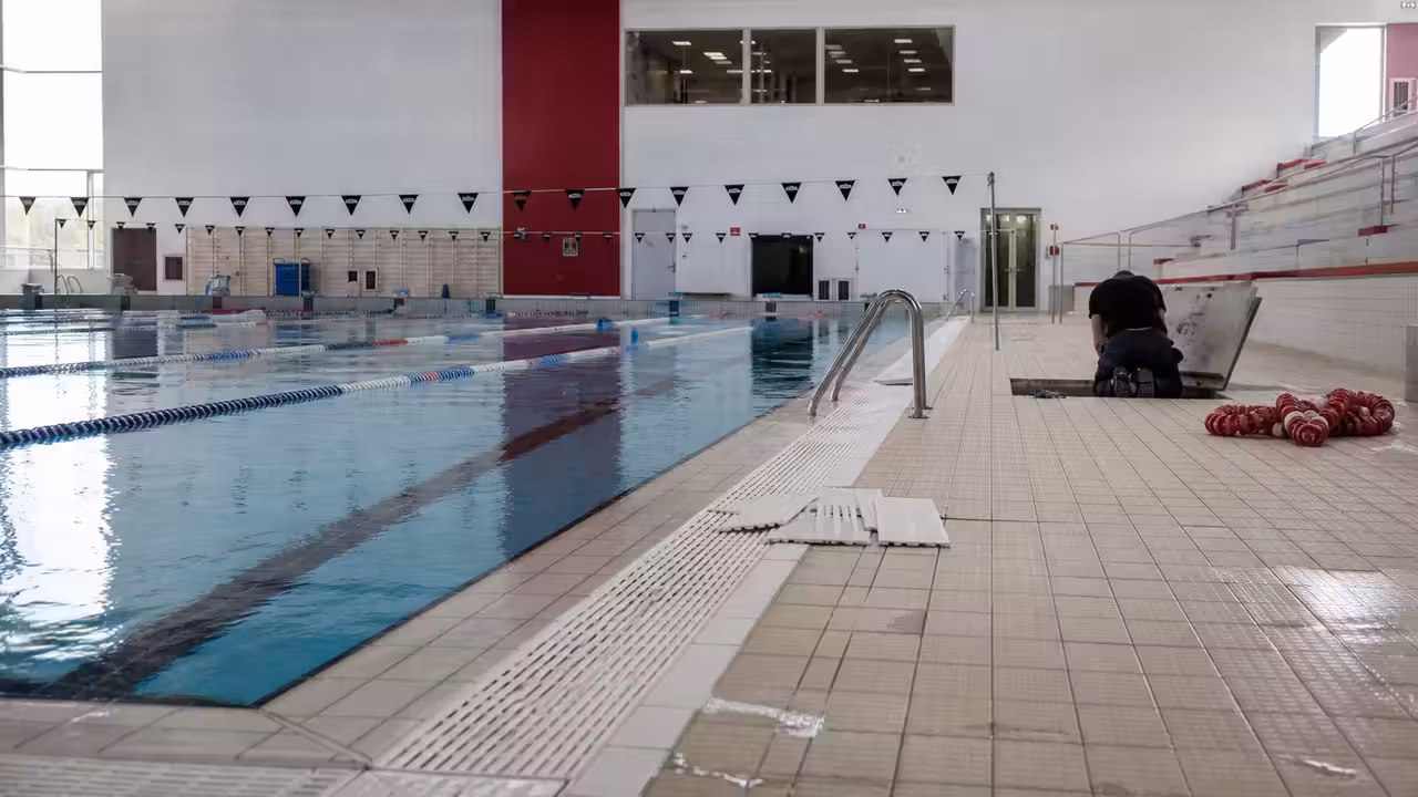 Bassin sportif intérieur vide pendant une maintenance technique dans un centre aquatique municipal