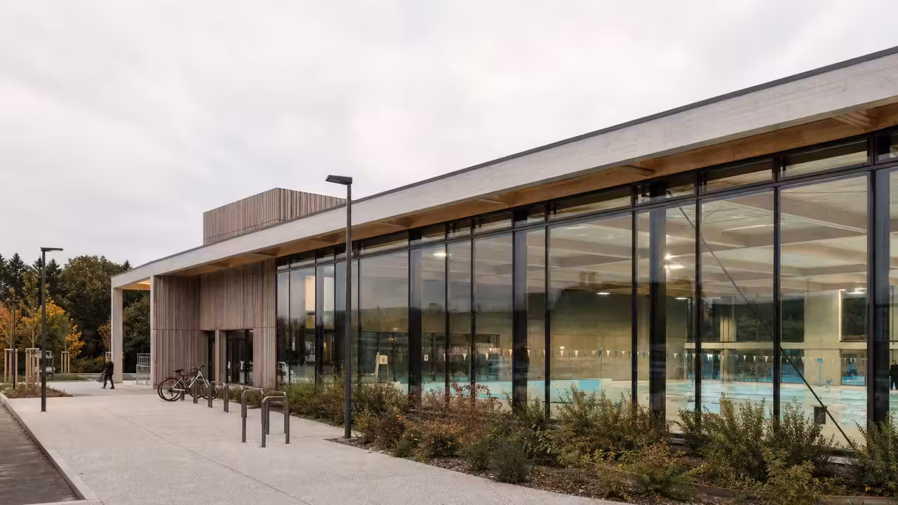 Bassin intérieur lumineux d’un centre aquatique public avec lignes de nage et accès adapté au bord de l’eau