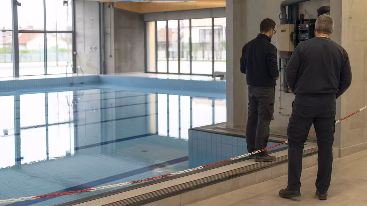 Petit bassin intérieur temporairement fermé, avec lignes d’eau et personnel technique au bord du bassin