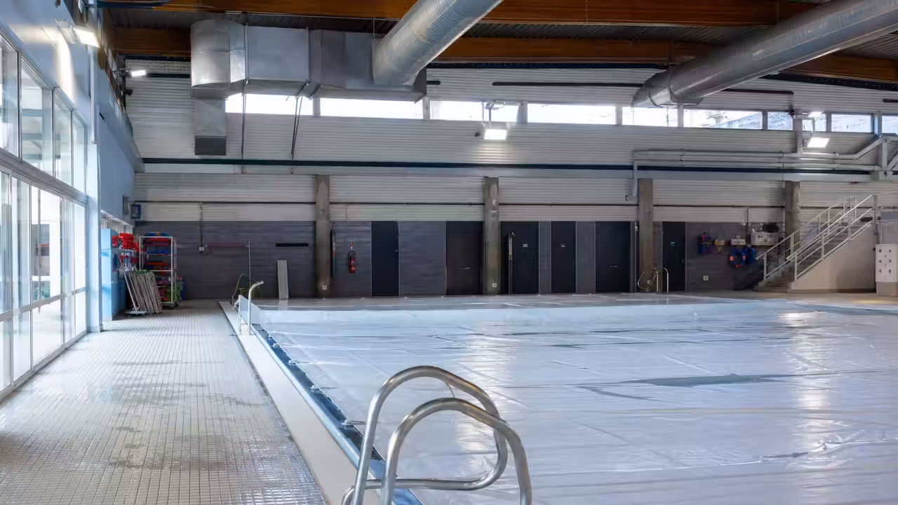 Bassin d’une piscine municipale vide et couvert pendant une fermeture hivernale, sous une lumière froide