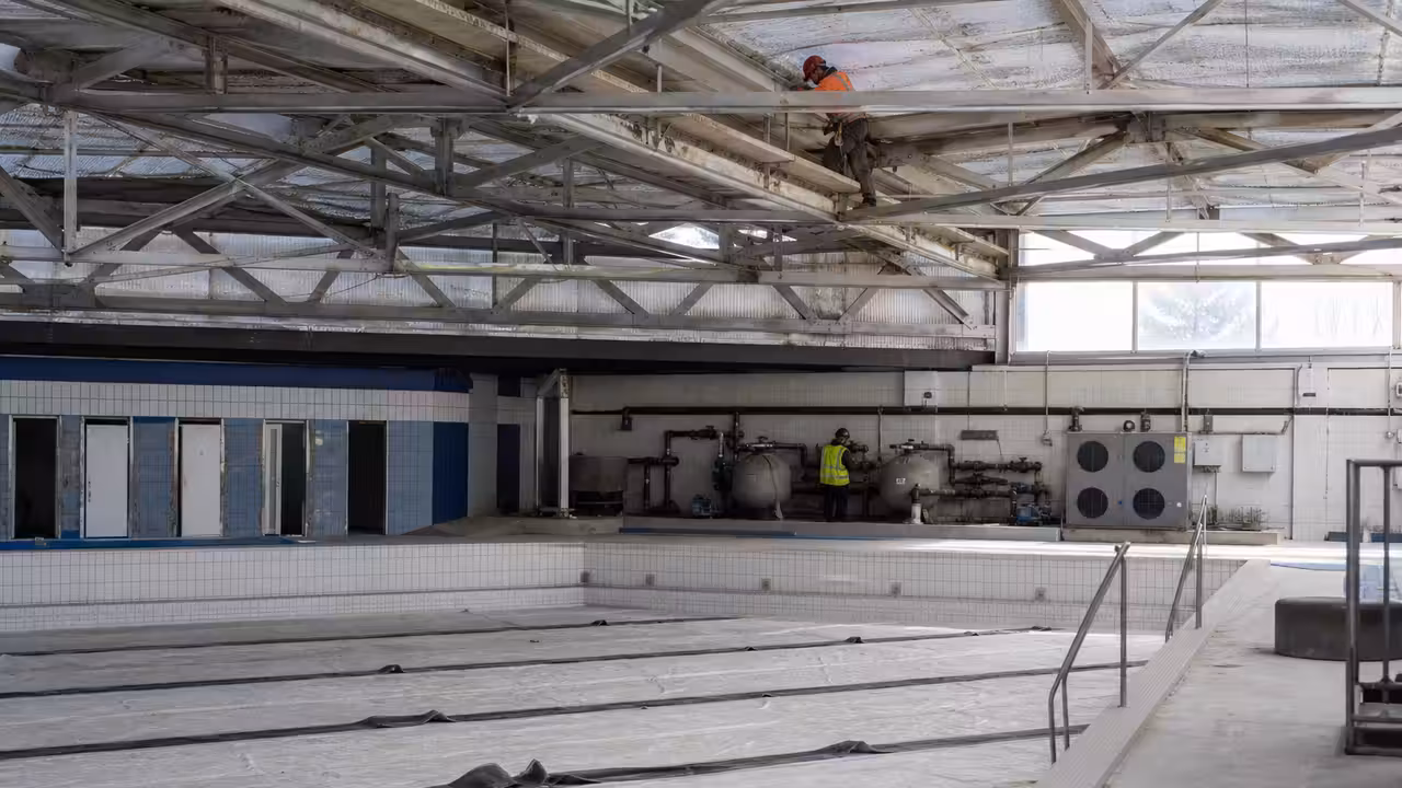 Bassin municipal de 25 mètres vide pendant des travaux de filtration et de consolidation de la charpente.