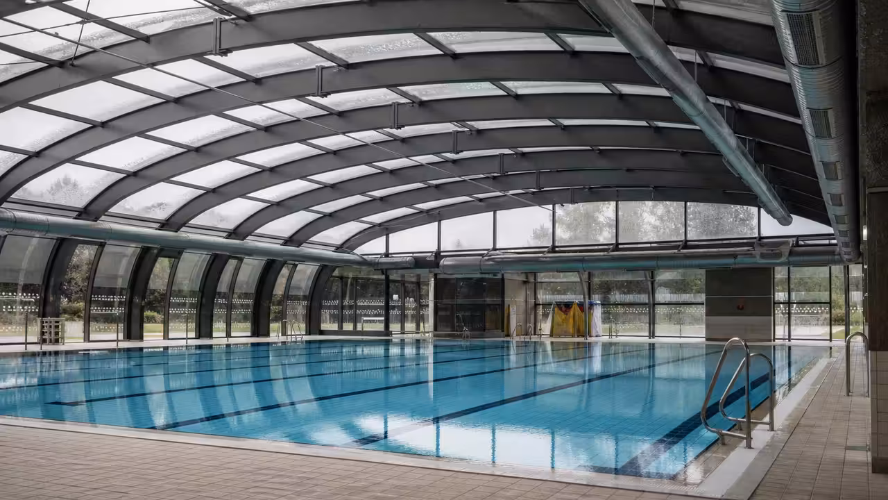 Hall de piscine couverte avec bassin vide, coupoles vitrées et lumière naturelle diffuse en journée