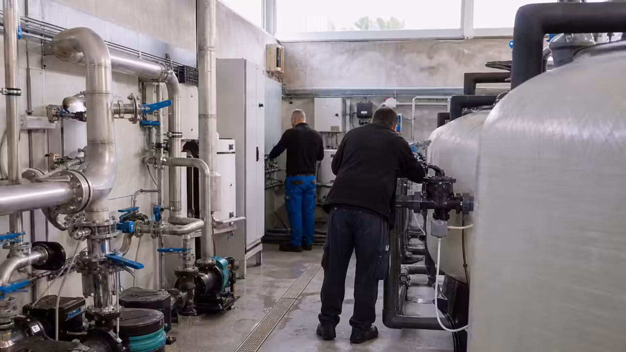 Local technique d’une piscine municipale avec pompes, filtres et canalisations en cours de maintenance
