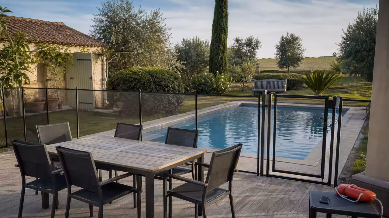 Terrasse de piscine rangée avant une réception, avec barrière fermée et mobilier éloigné du bassin