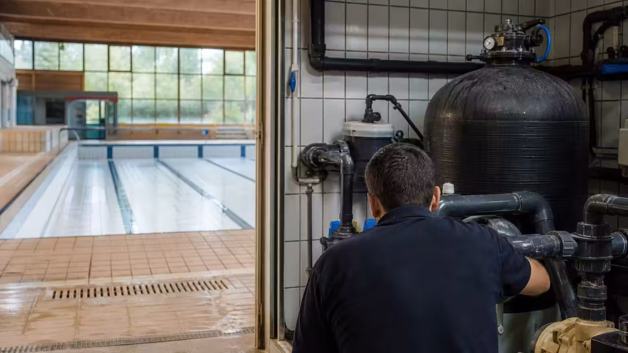 Technicien contrôlant les équipements de filtration d’une piscine publique vide pendant un arrêt de maintenance