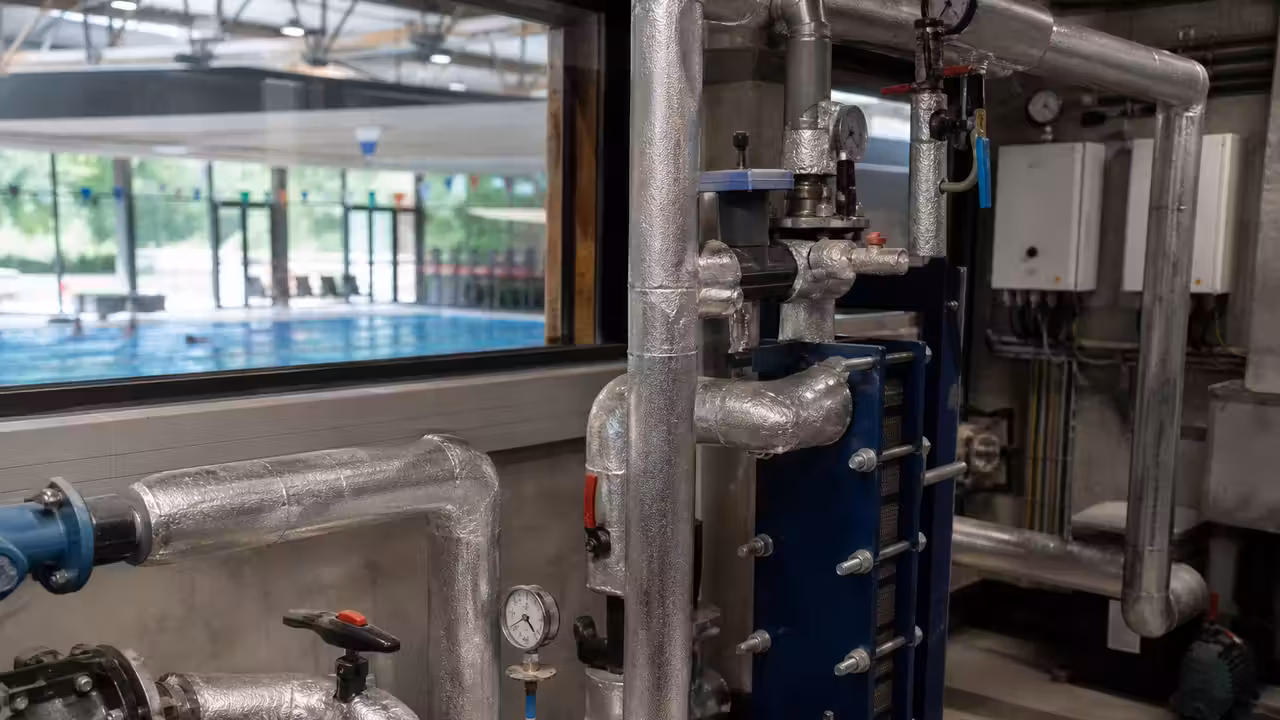 Local technique d'une piscine publique avec canalisations isolées et échangeur de récupération de chaleur