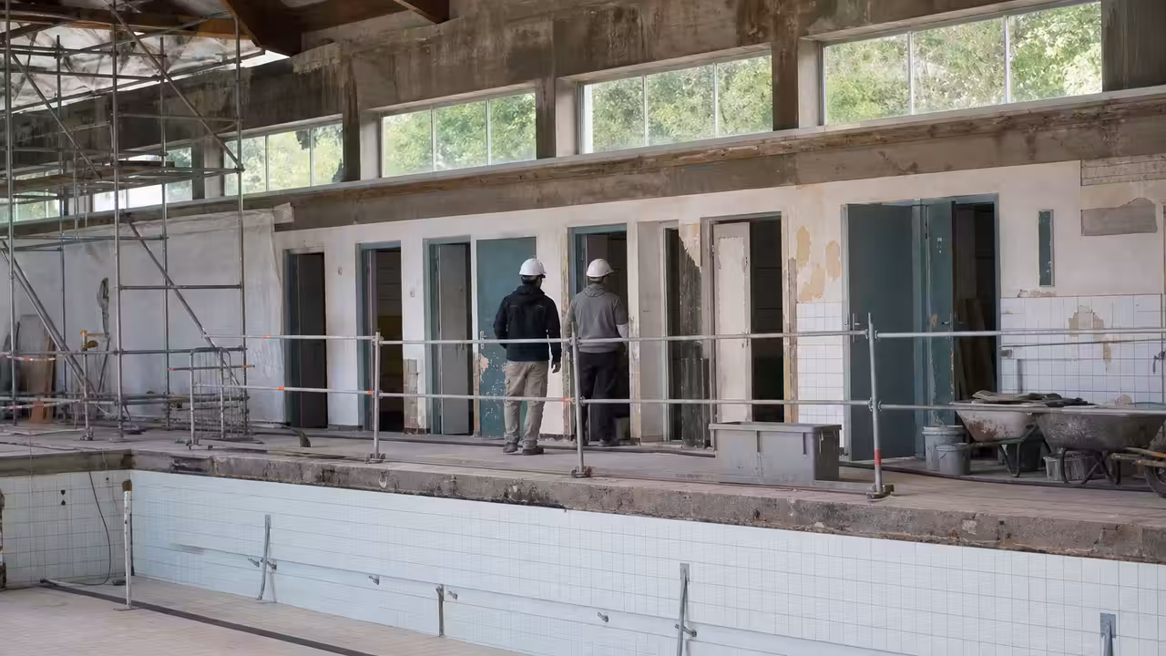 Chantier de rénovation d’une piscine municipale avec bassin vidé, échafaudages et vestiaires en travaux