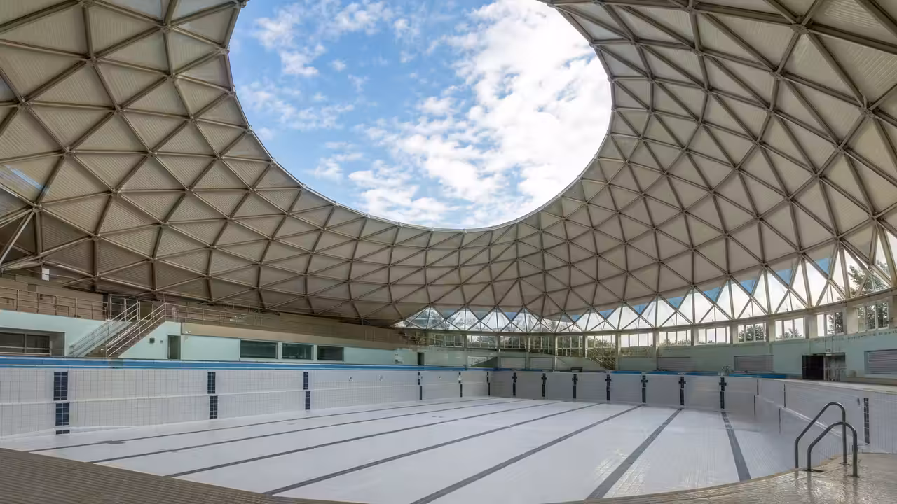 Coupole géodésique d’une piscine publique des années 1970 ouverte sur un bassin rénové et lumineux