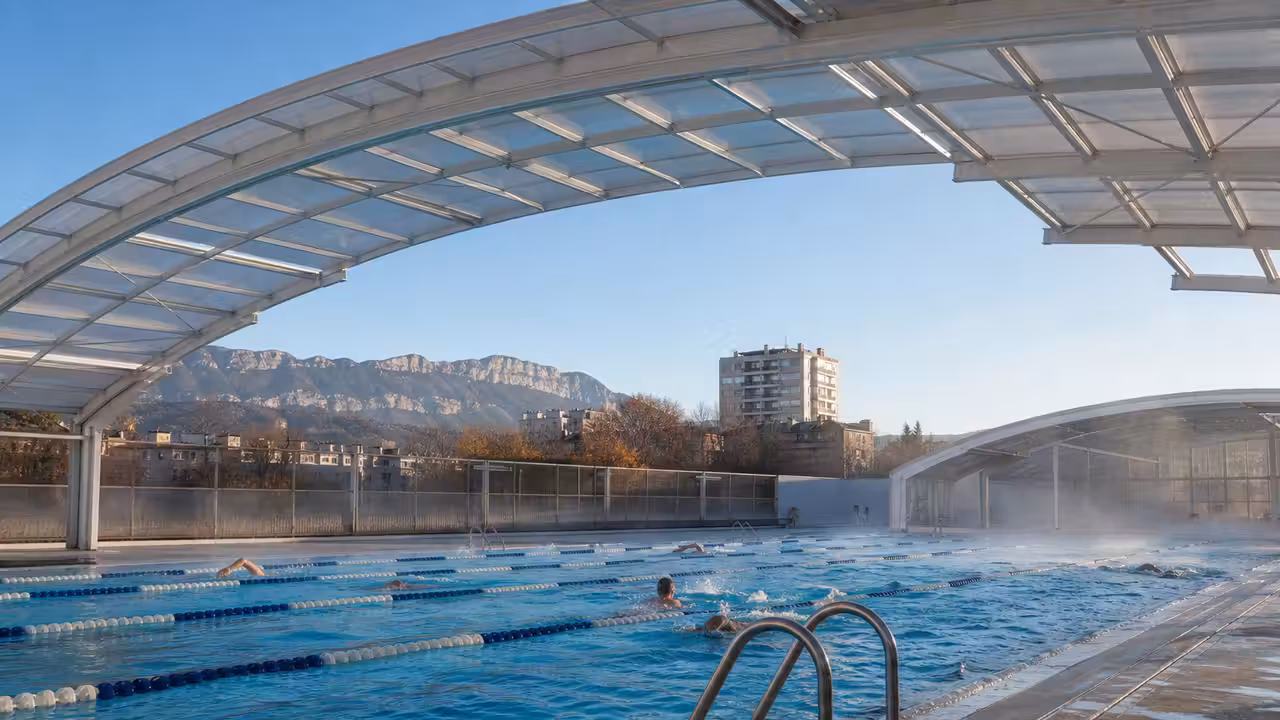 Bassin extérieur chauffé d’une piscine municipale, avec couloir de nage et structure de couverture légère