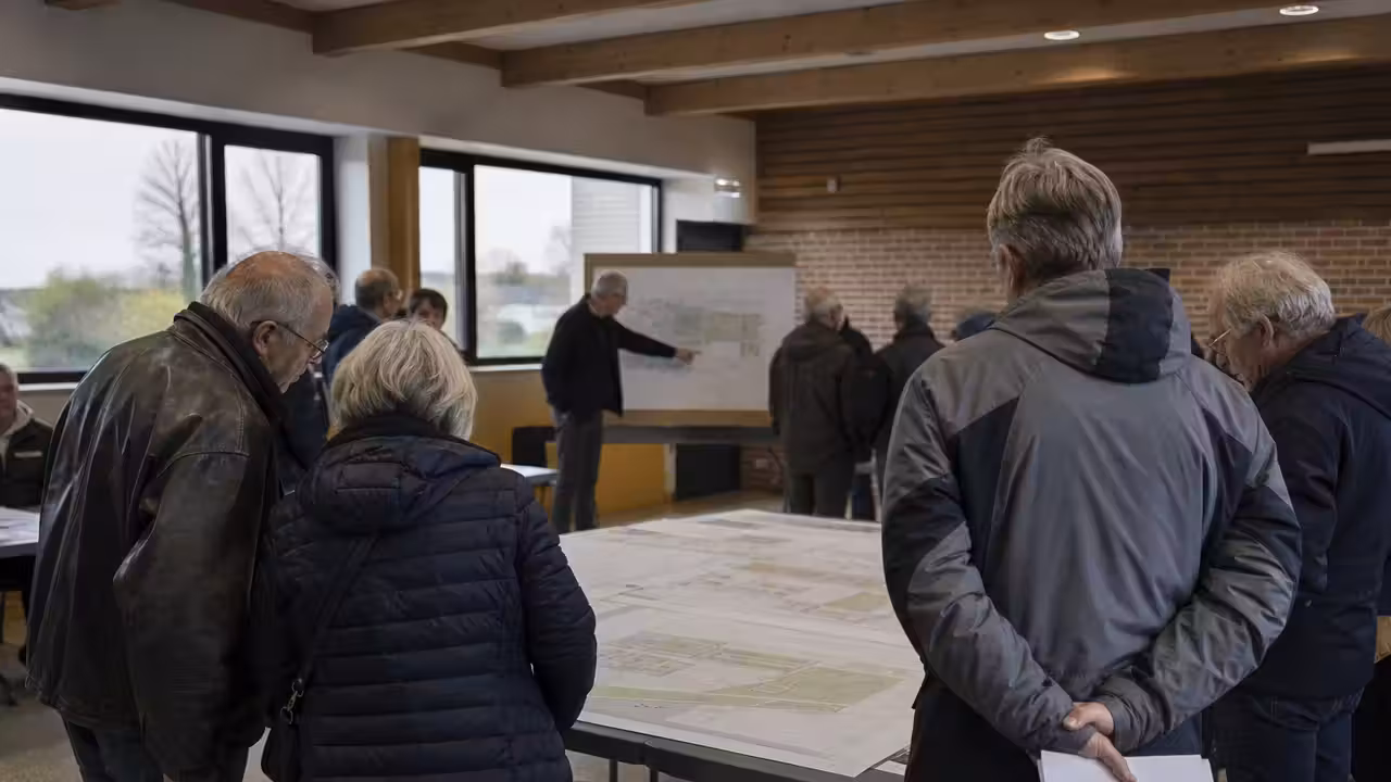 Réunion publique consacrée à un projet de piscine municipale, avec plans de bassin et habitants au premier plan.