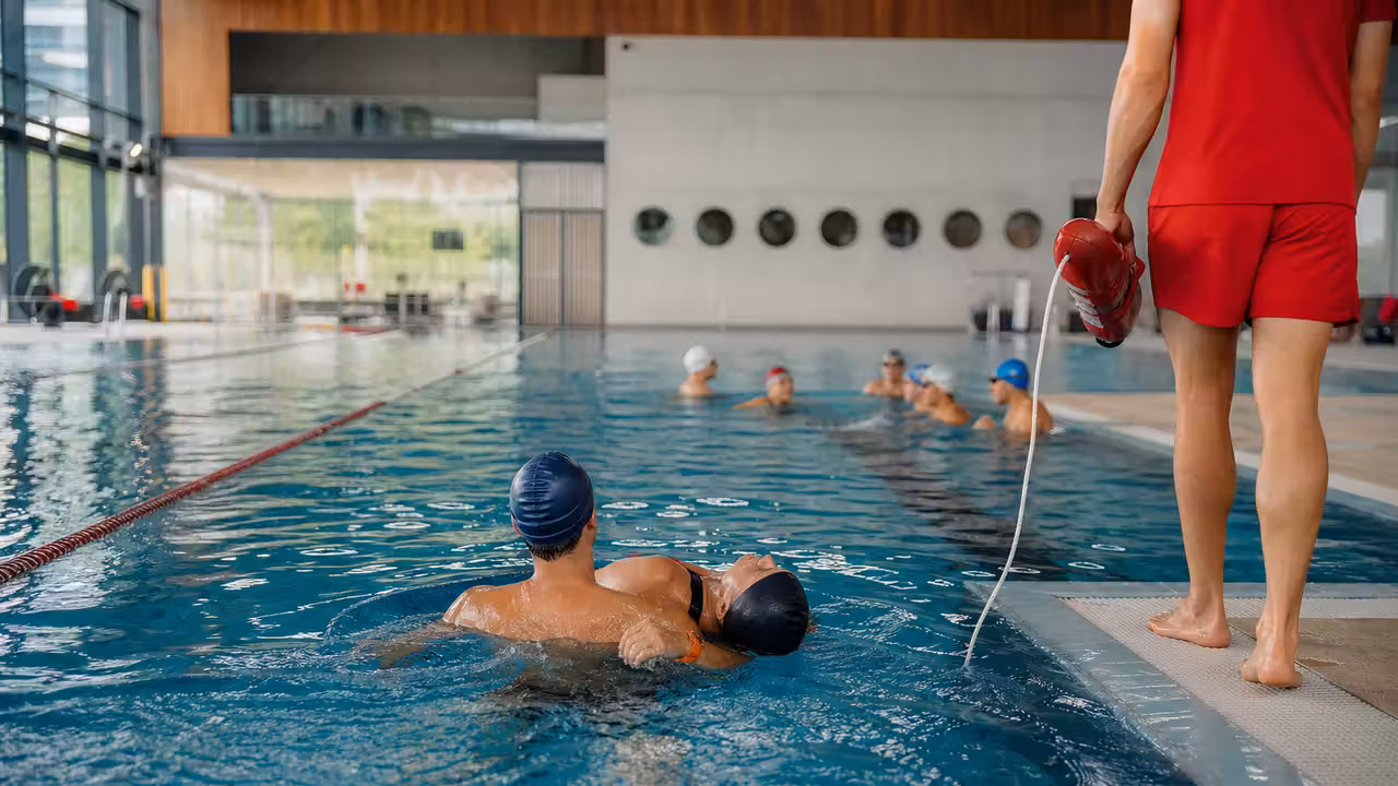 Exercice de sauvetage encadré entre adultes dans le bassin d’une piscine publique couverte